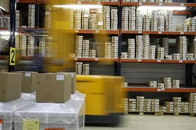 Een warehouse gevuld met pakketjes met een heftruck die door de schappen rijdt
