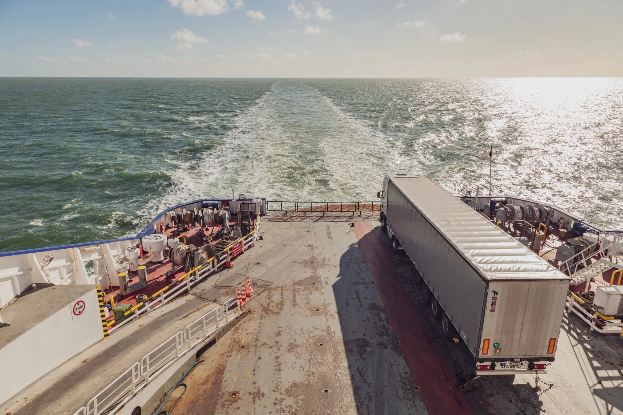 Vrachtwagen staat geparkeerd op een schip die aan het varen is.