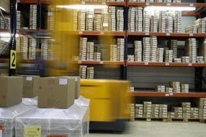 Een warehouse gevuld met pakketjes met een heftruck die door de schappen rijdt